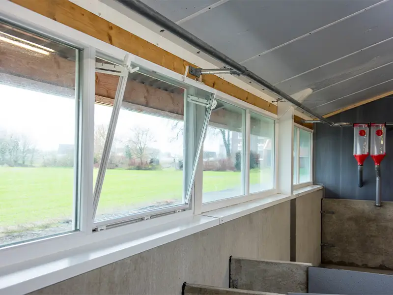 Binnenzijde openstaande kunststof valramen in stal